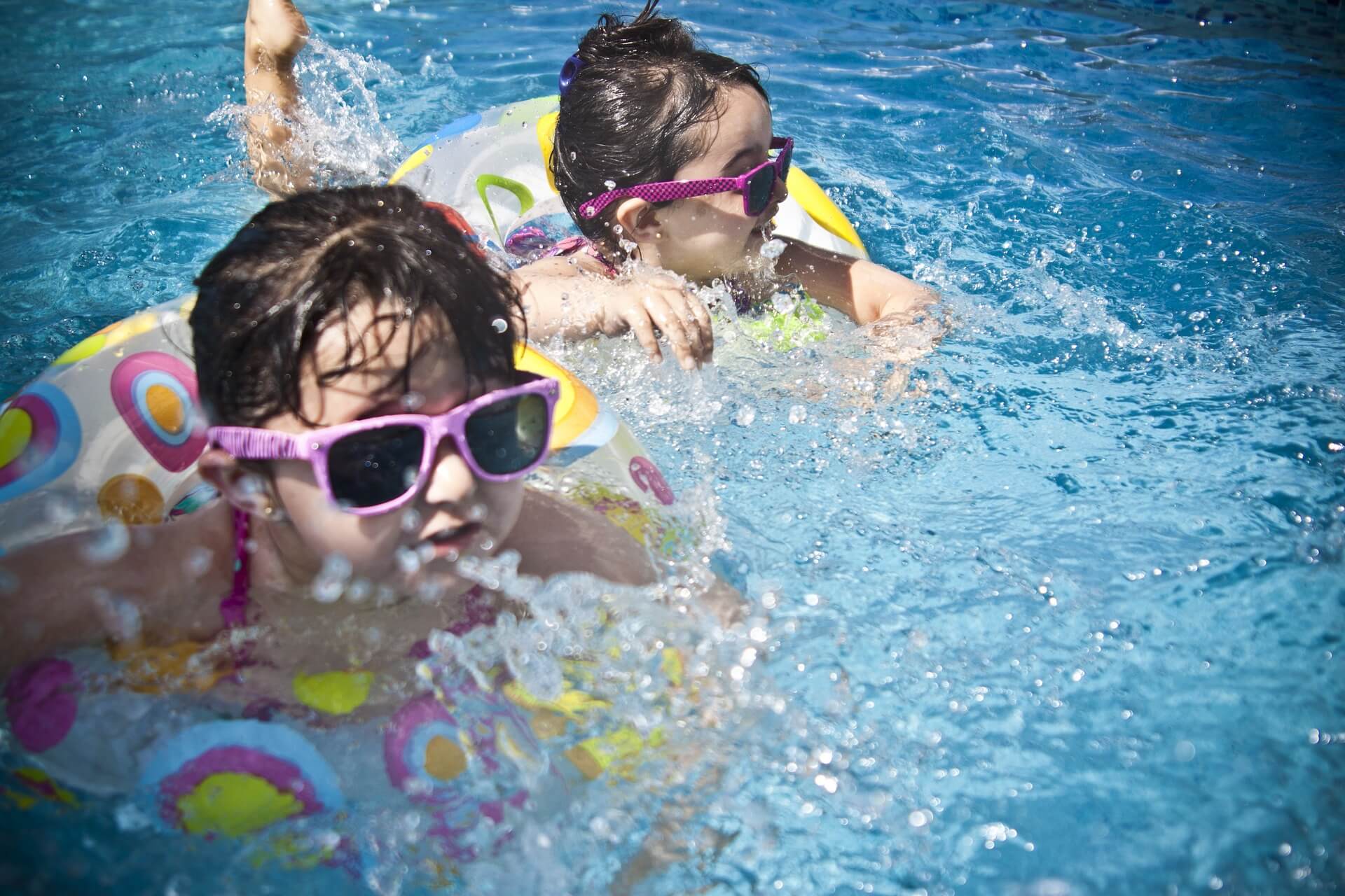 Kinder, die im Pool mit Schwimmreifen schwimmen
